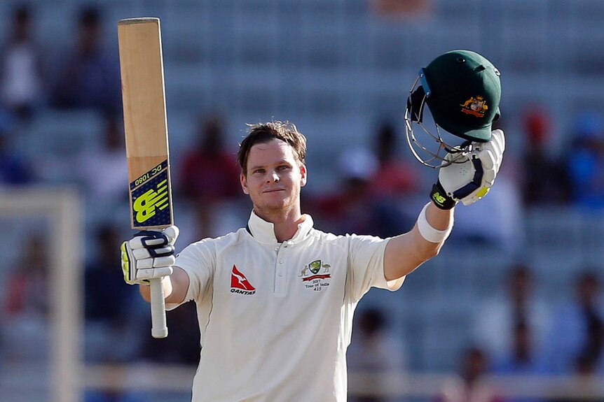 Australia's Steven Smith raises his bat and helmet after reaching his century in Ranchi