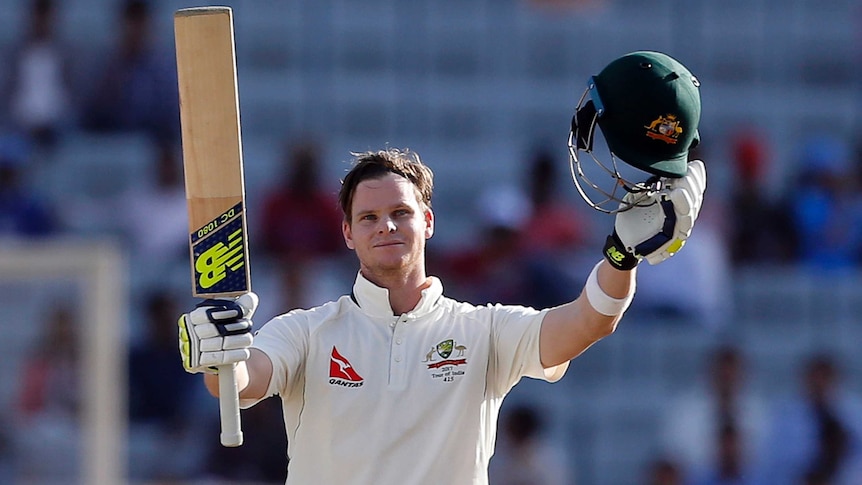 Australia's Steven Smith raises his bat and helmet after reaching his century in Ranchi