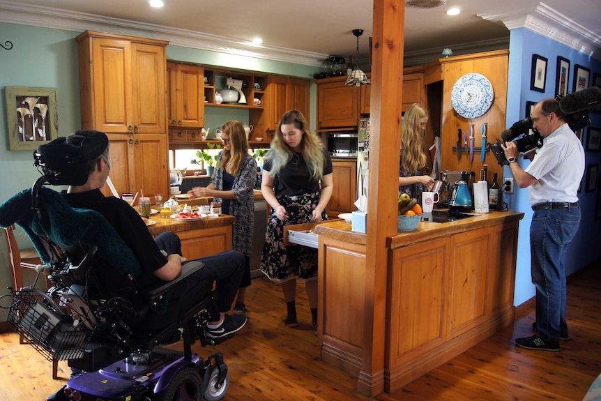 Cameraman Quentin Davis filming the Yerbury family in their kitchen as Justin in wheelchair looks on.