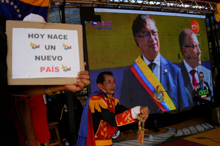 A monitor showing president Gustavo Petro with a sign in the foreground which reads Hoy Nace Un Nuevo Pais
