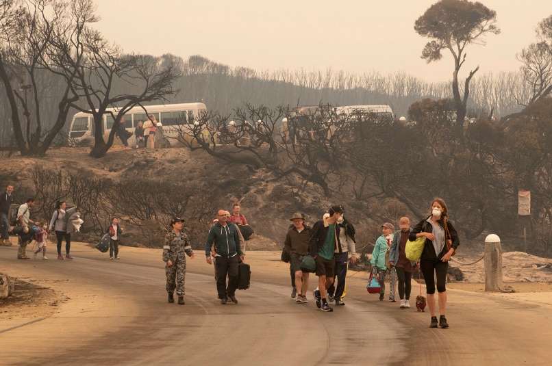 Bushfire evacuees walk down to the beach at Mallacoota pictured in story about bushfire trauma.