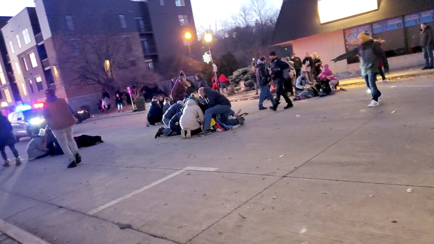 People attend to injured victims in the street. 