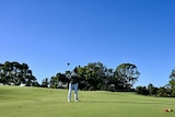 A golf course fringed by trees.