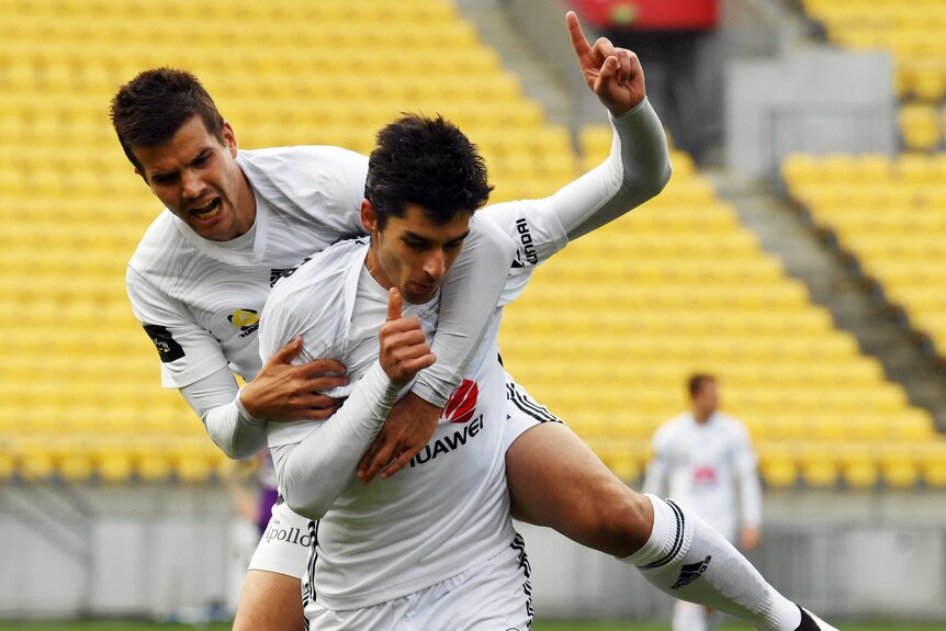 Andrija Kaludjerovic jumps on the back of Gui Finkler as they celebrate a Wellington Phoenix goal.