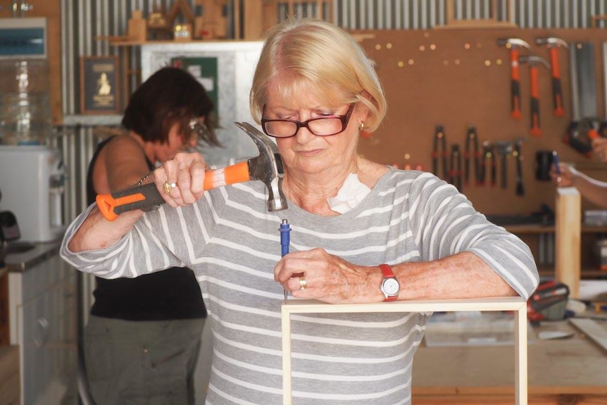 Workshop attendee hammers a nain into wood.