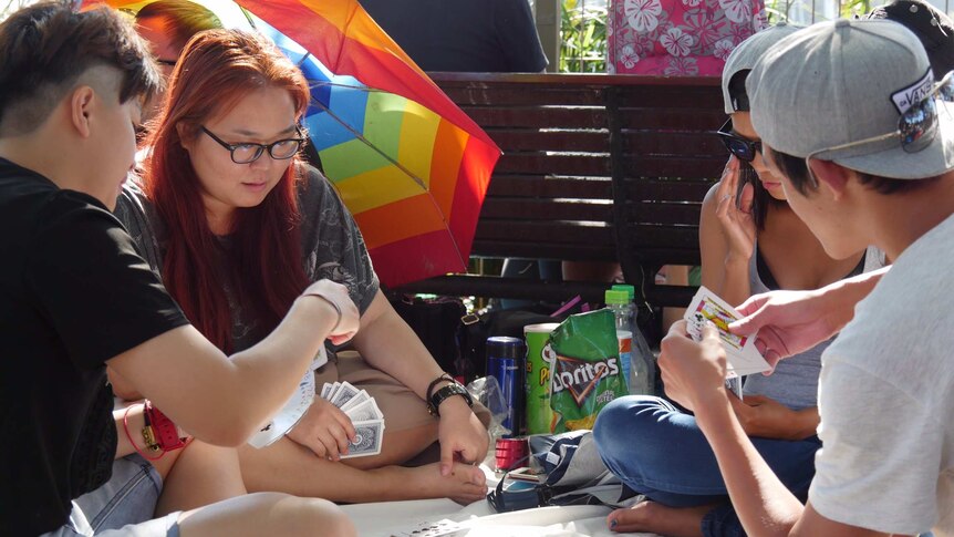 Groups of people play cards as they kill time at Mrs Macquarie's Chair ahead of the fireworks.