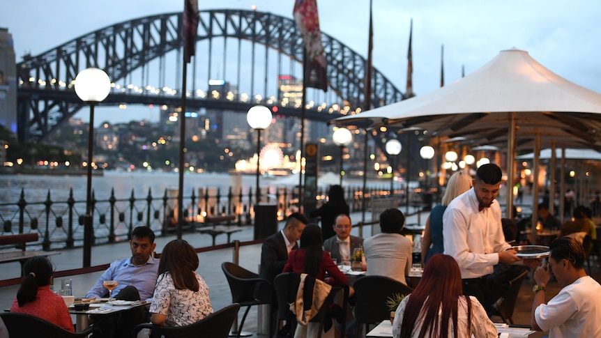 people dining in candle light by Sydney Harbour Bridge