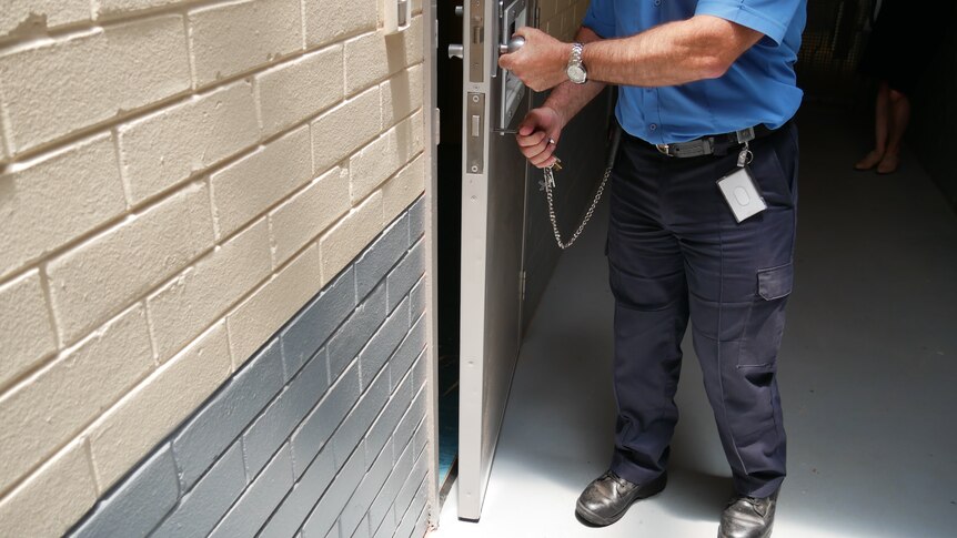 An officer unlocking a prison cell.