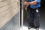 An officer unlocking a prison cell.
