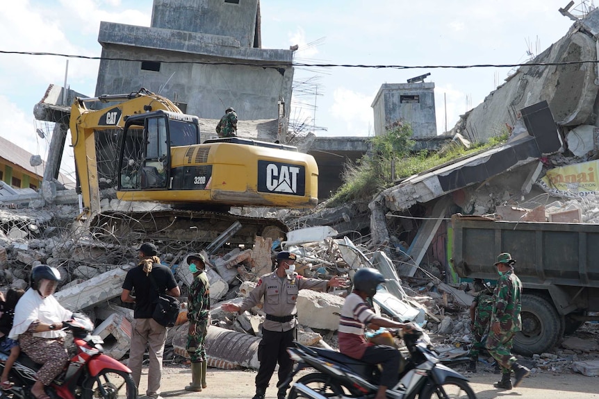 Rescue workers use a bulldozer to look for earthquake victims in Indonesia.