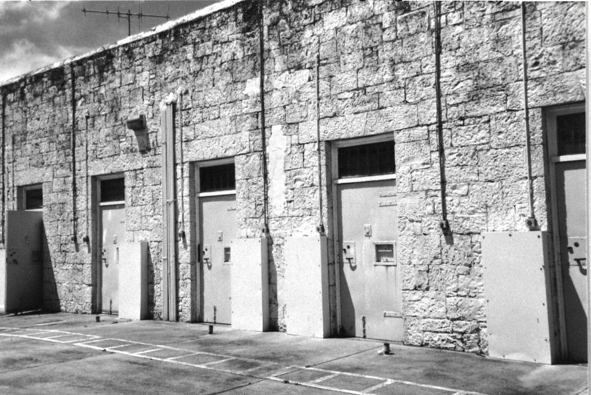 Black and white photo of an old stone prison with doors opening onto a courtyard