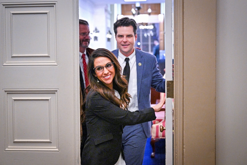 Lauren Boebert smiling as she opens an office door with Matt Gaetz behind her