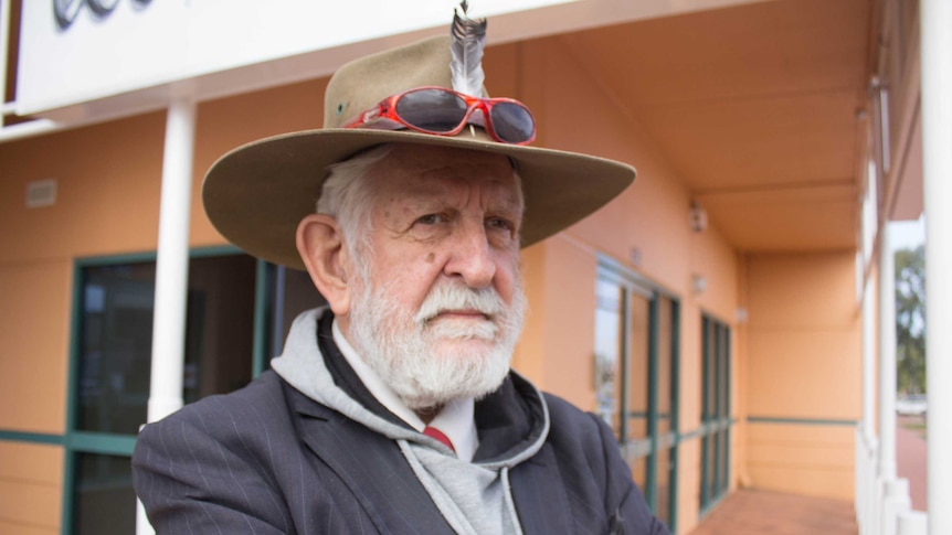 An elderly man stands with his arms folded outside a building in Kalgoorlie.