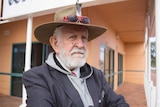 An elderly man stands with his arms folded outside a building in Kalgoorlie.