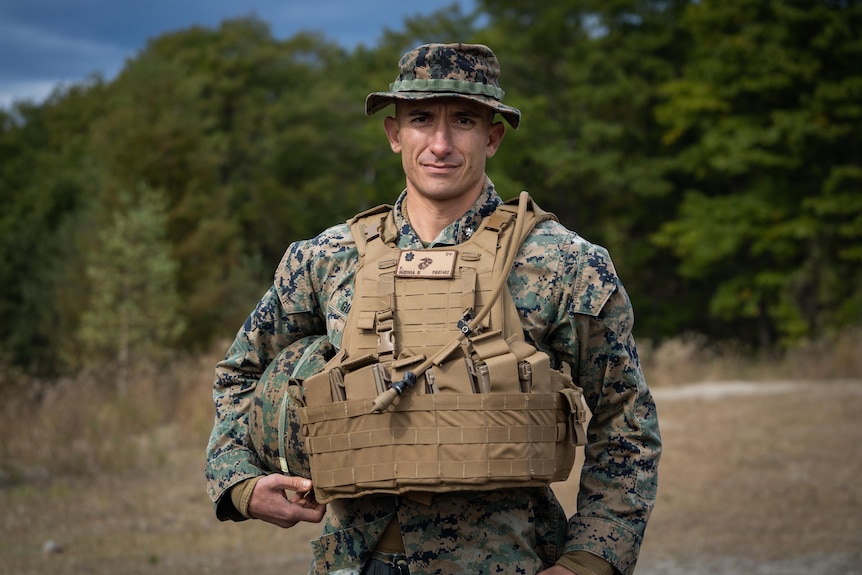 A soldier in army fatigues and a khaki vest 