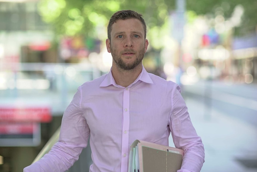 Josh Mennen stands on a busy Sydney street.