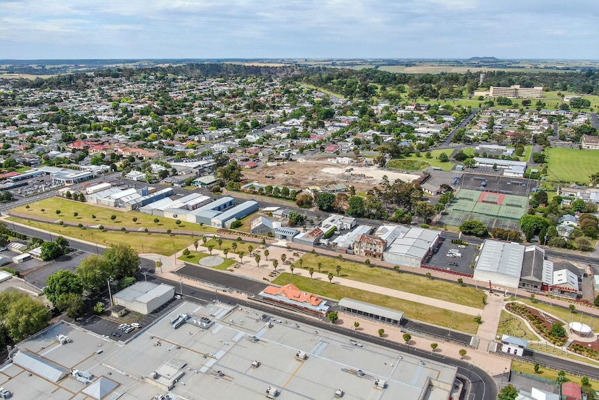 A drone shot looks down on a green city with a long bike trail slashed through it