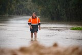 A man walks through knee-deep floodwaters in Echuca