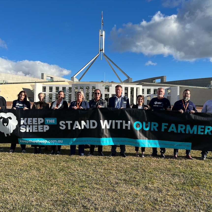 A group of people stand outside Canberra parliament house holding a banner reading "Keep The Sheep: Stand with our farmers".