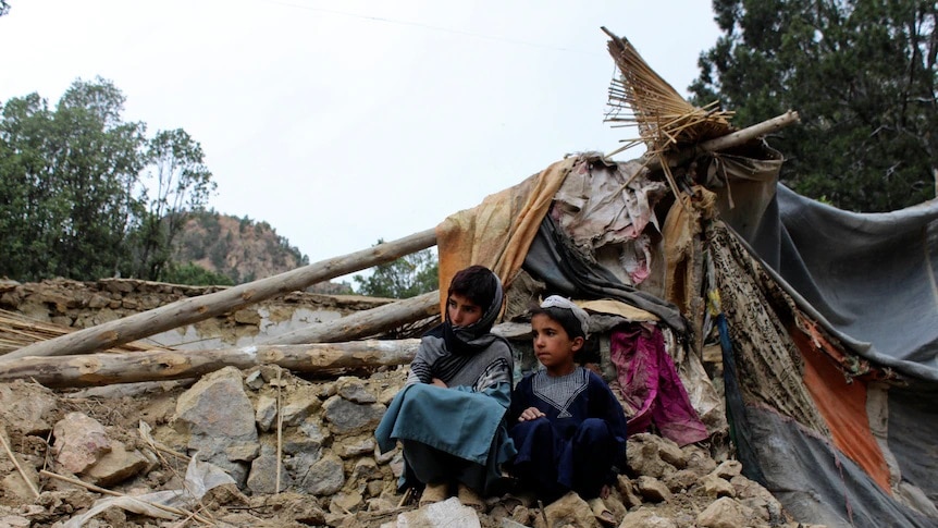 Two children sit amongst the rubble after an earthquake struck Afghanistan