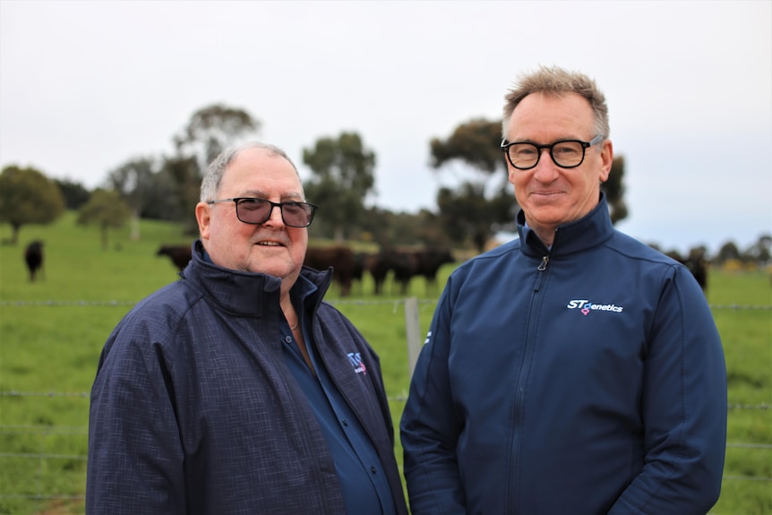 Photo of two men standing a smiling on a farm.