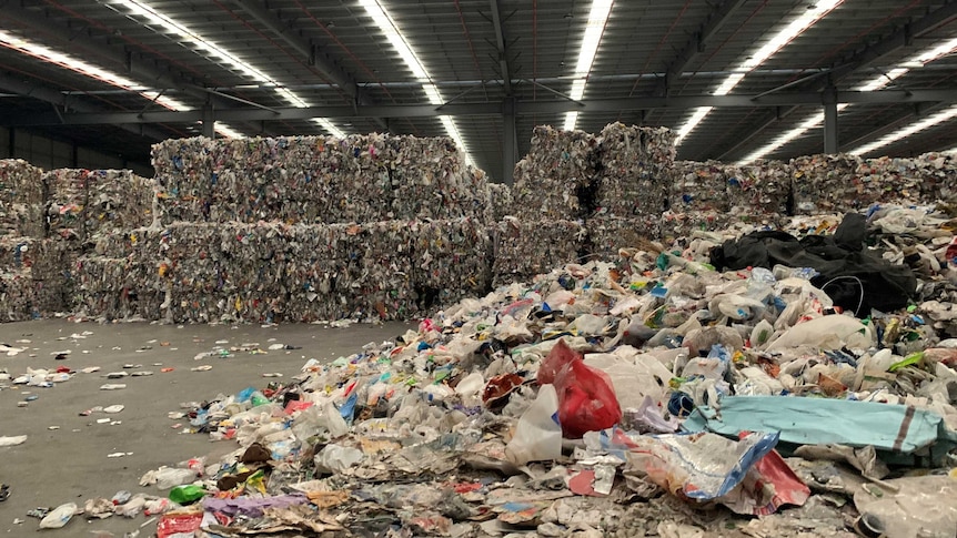 Large cubes of plastic waste bundled in a huge warehouse.