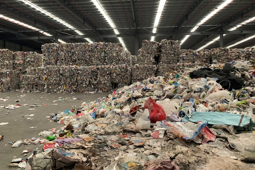 Large cubes of plastic waste bundled in a huge warehouse.