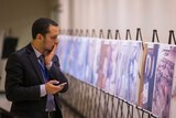 Man looks at collection of images of dead bodies