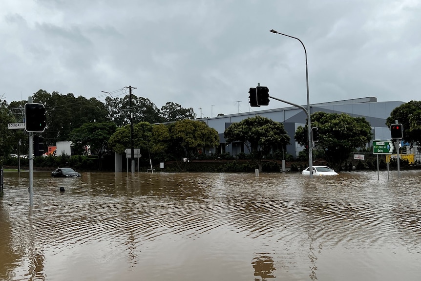 Two cars stuck in floodwaters at intersection on Blunder Road at Oxley
