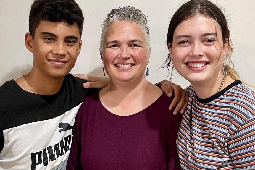 A woman with short grey hair stands with her two children.