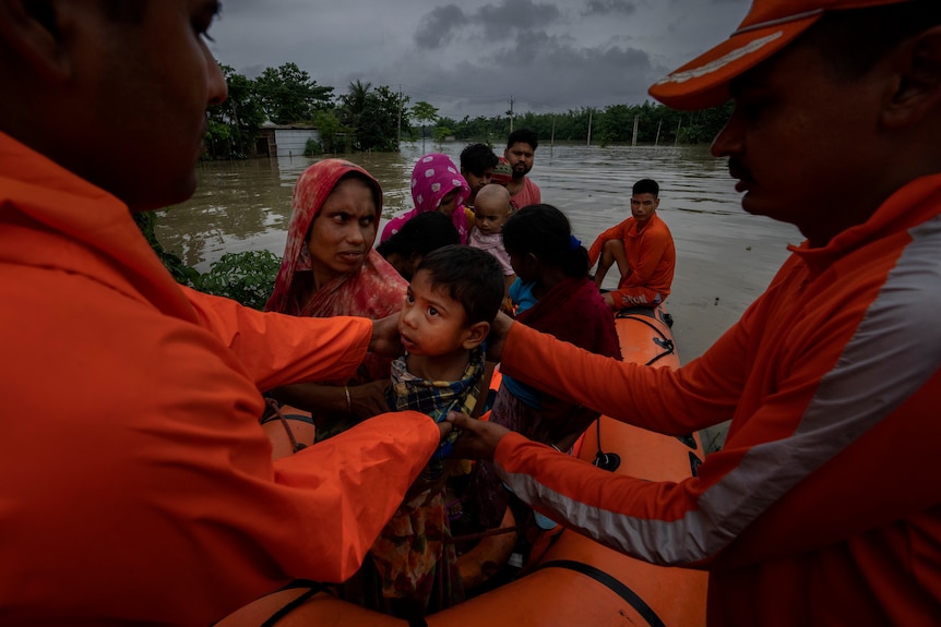 National Disaster Response Force (NDRF) personnel rescue flood-affected villagers in a speed boat in Korora village.