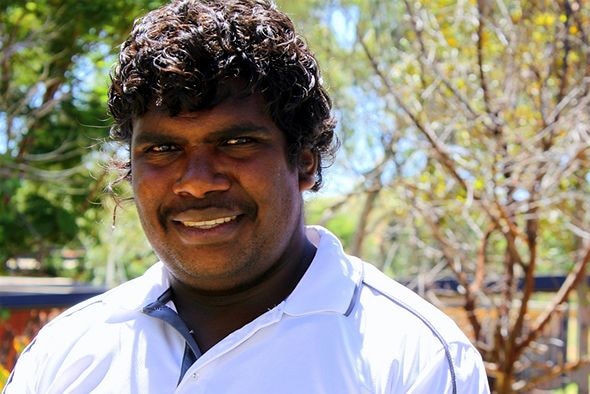 an Indigenous man in a white shirt, smiling