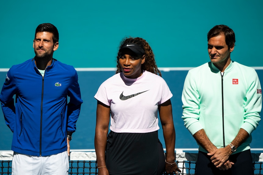 Novak Djokovic, Serena Williams and Roger Federer stand at the net on a tennis court.