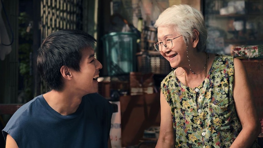 A young man and an older woman smile at each other. 