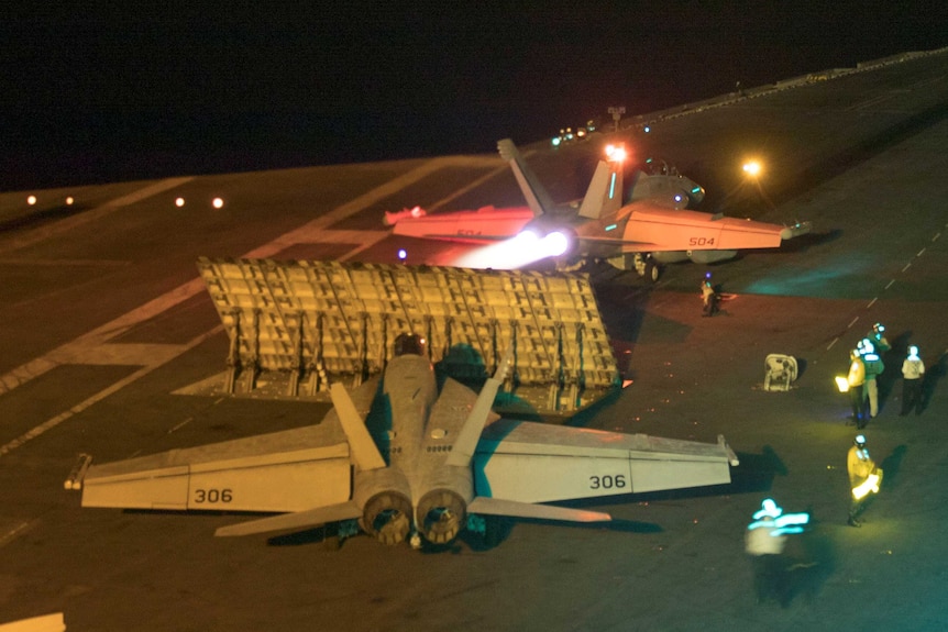 A plane taking off from an aircraft carrier at night