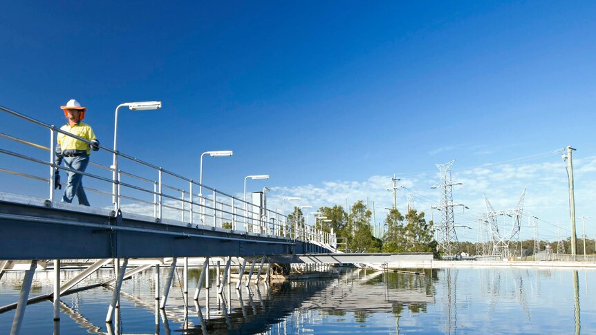 A man walks on a bridge over an Urban Utilities water storage
