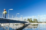A man walks on a bridge over an Urban Utilities water storage