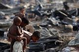 Boys search for items among the ashes of burnt houses.