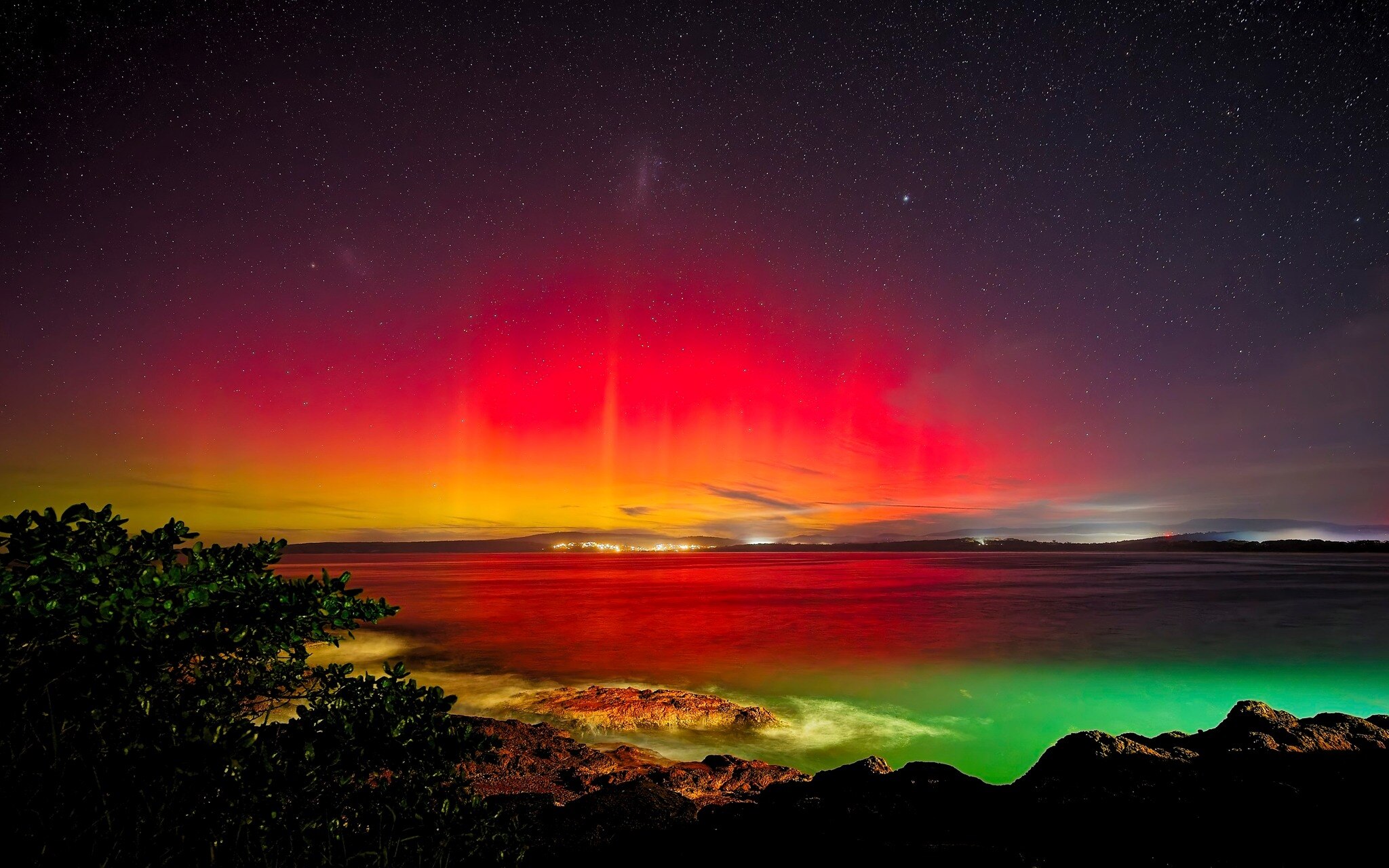 Red and yellow light glows over a bay. 