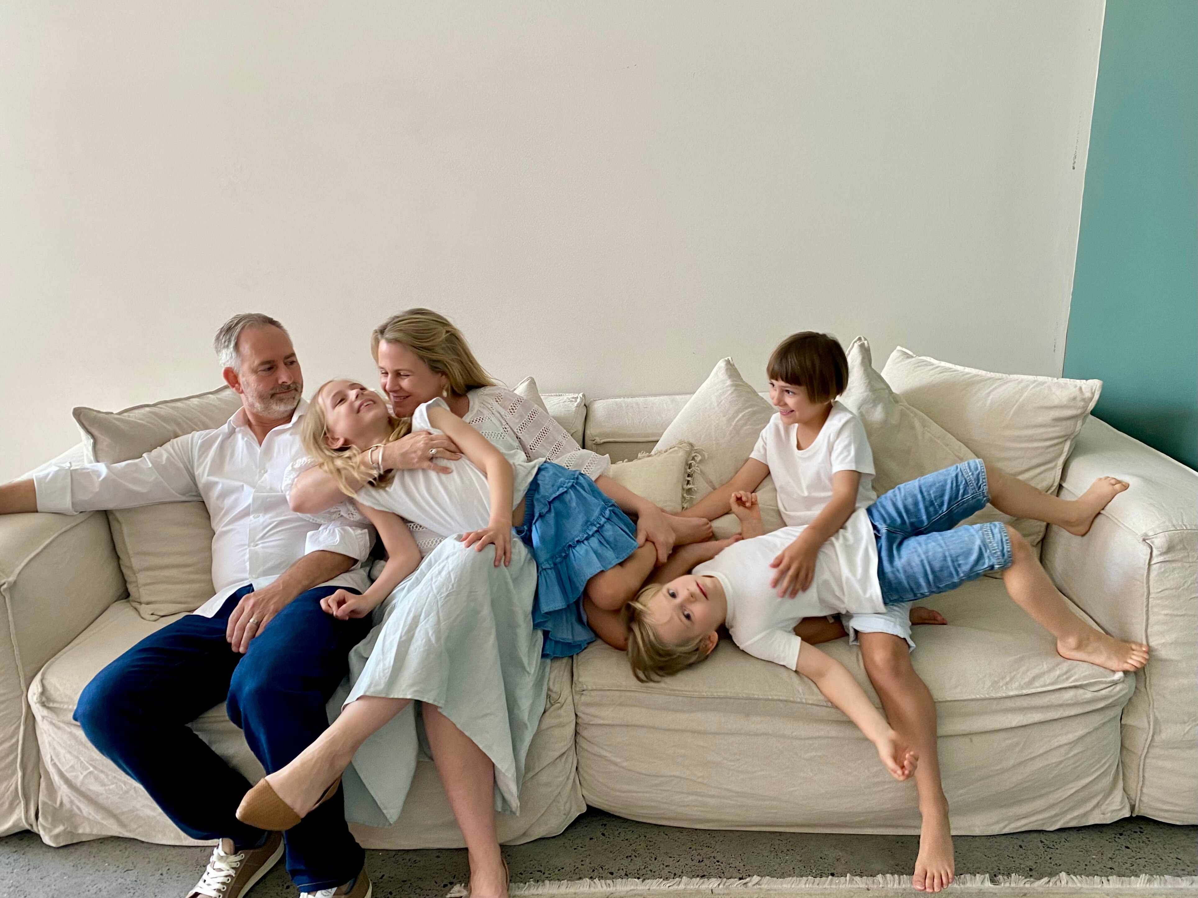 two parents and their three children pose together on a cream couch