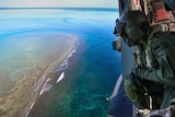 An Australian naval officer looks out of a helicopter over Elizabeth Reef in search of unexploded ordnance.
