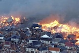 Houses swept out to sea burn following a tsunami and earthquake in Japan