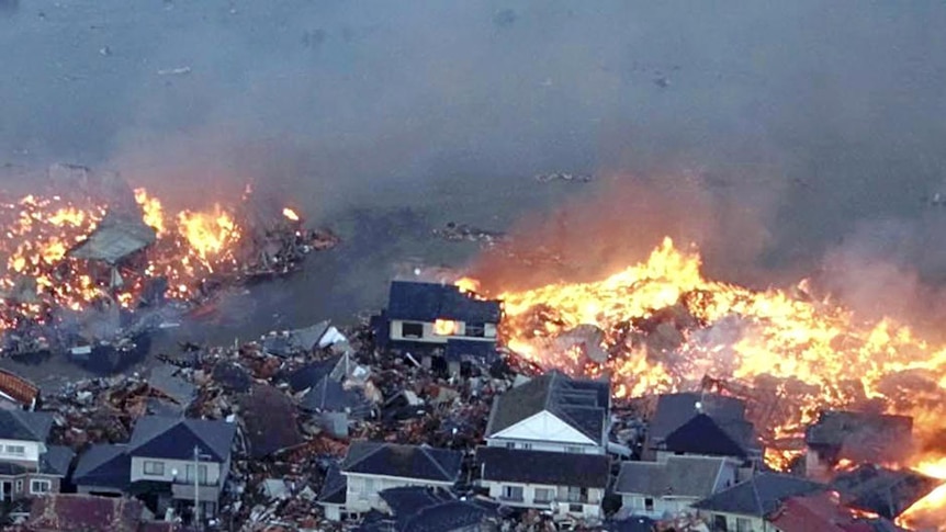 Houses swept out to sea burn following a tsunami and earthquake in Japan