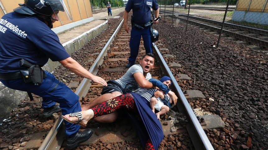 Hungarian policemen stand by the family of migrants