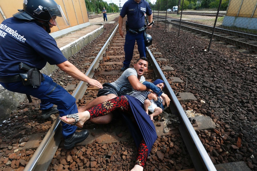 Hungarian policemen stand by the family of migrants