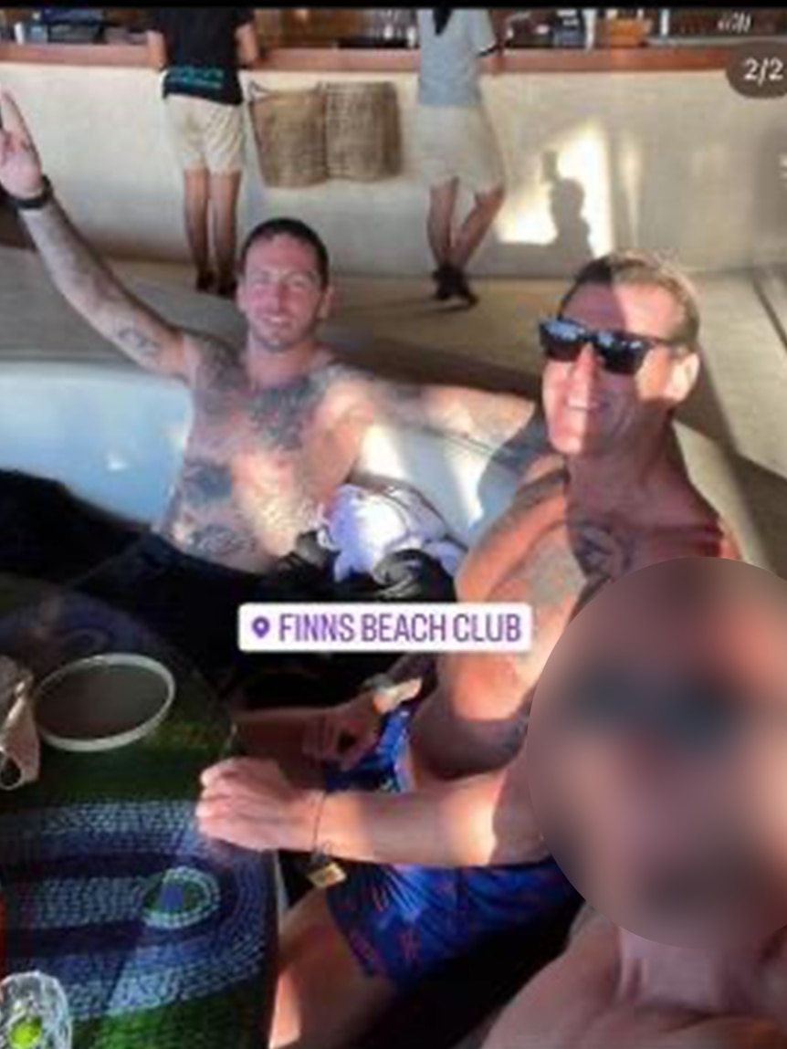 three shirtless men at a beach club drinking alcohol
