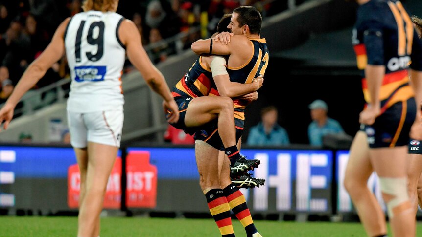 Lachlan Murphy has his legs wrapped around Taylor Walker's waist as the two embrace lovingly.