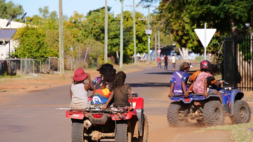 Children riding quad bikes on a rural street
