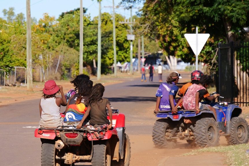 Children riding quad bikes on a rural street