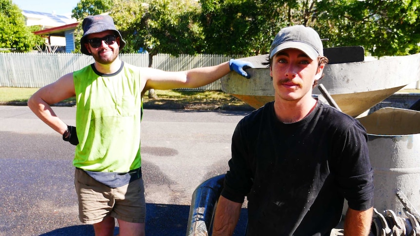 Two young guys look dashing and relaxed against truck. Both with hats but Owen's sandals are probably not considered correct PPE